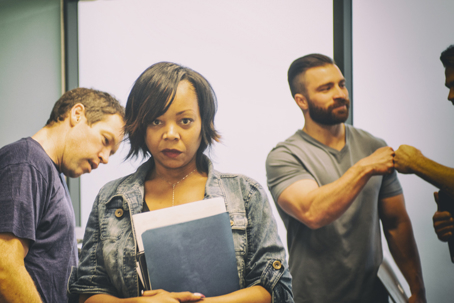 An upset woman walking from a group of male co-workers