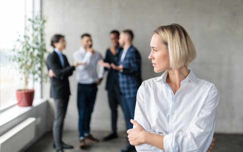 troubled woman in front of a group of male coworkers